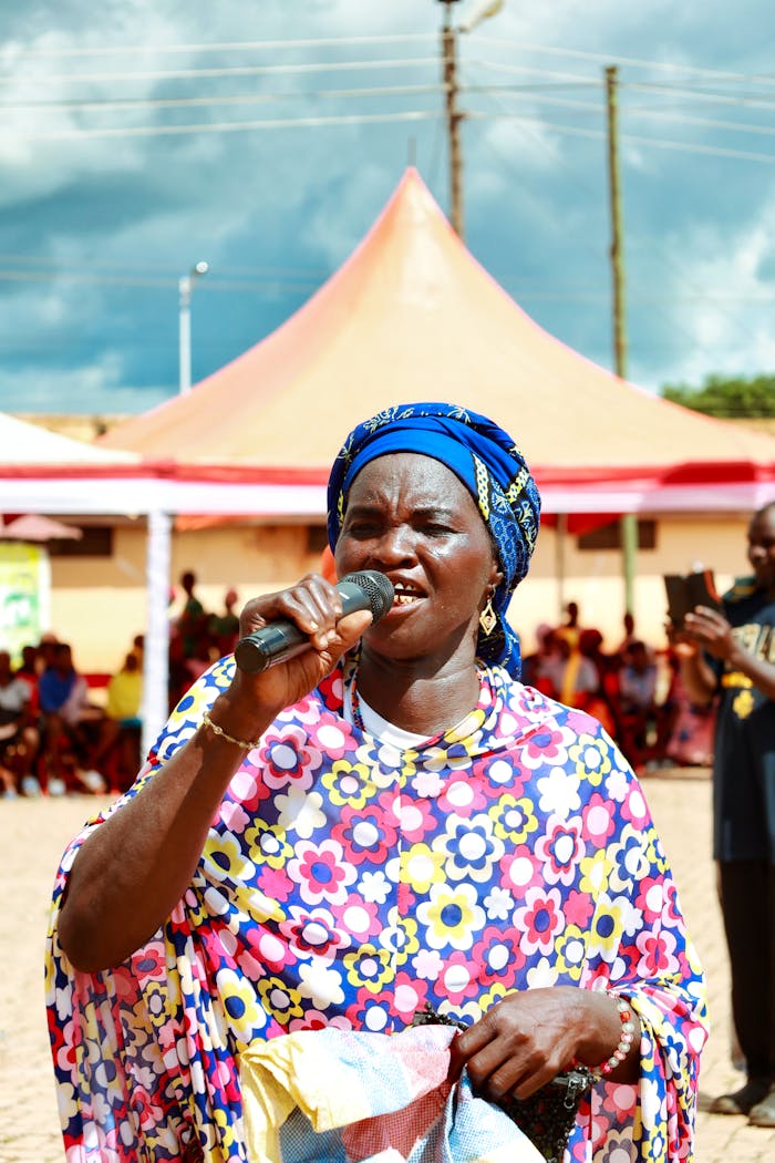 services-img A joyful African woman in vibrant attire singing outdoors at a cultural event in Ghana.
